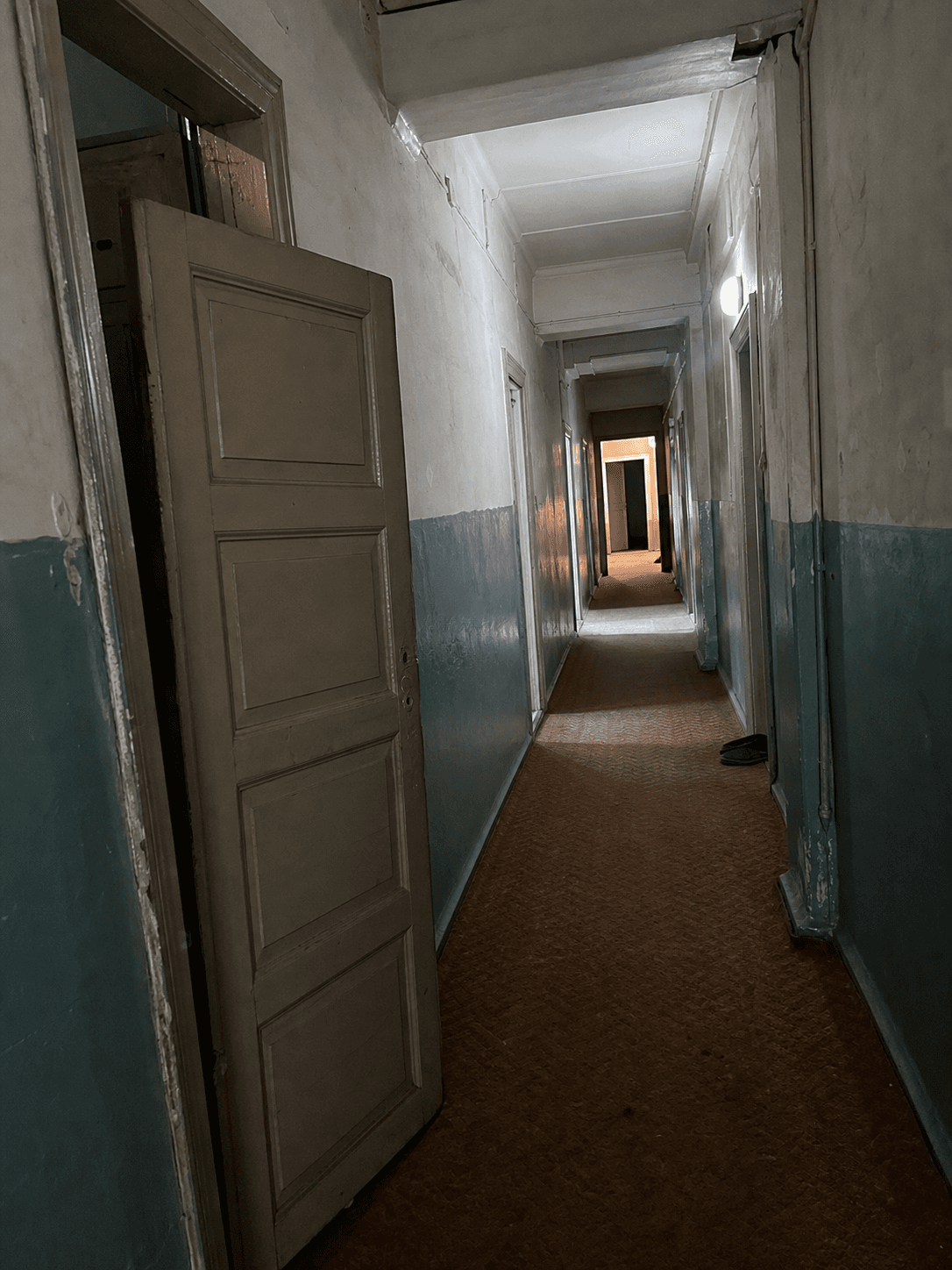 Aralık kapılı, boş ve sessiz görünen eski bir bina koridoru